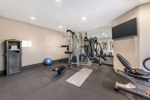 A gym with various exercise equipment, a bench, a mat, and a ball.