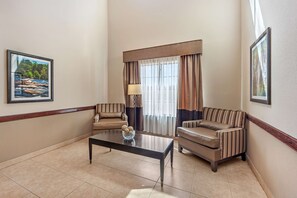 A hotel room with a large window, two sofas, a coffee table, and framed pictures on the walls. - Best Western La Grange Inn & Suites (La Grange)