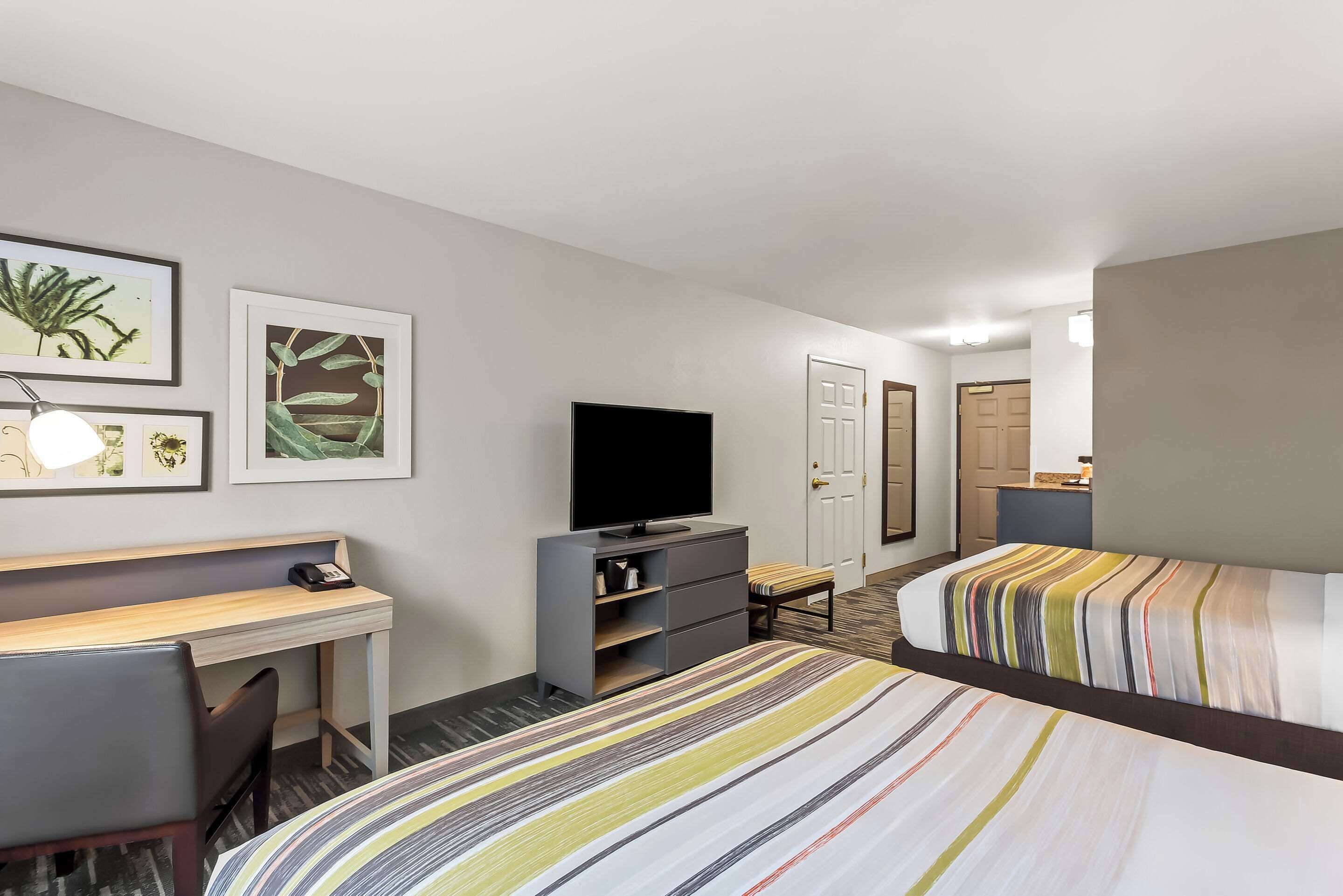 Habitación de hotel con cama, escritorio, televisor y obras de arte en la pared.