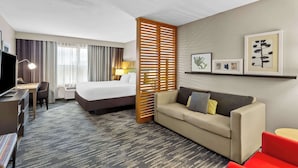 A hotel room with a bed, a sofa, a desk, and a TV. - Country Inn & Suites by Radisson, Portage, IN (Portage)