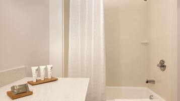 A bathroom with a shower, a bathtub, and a sink area with toiletries.