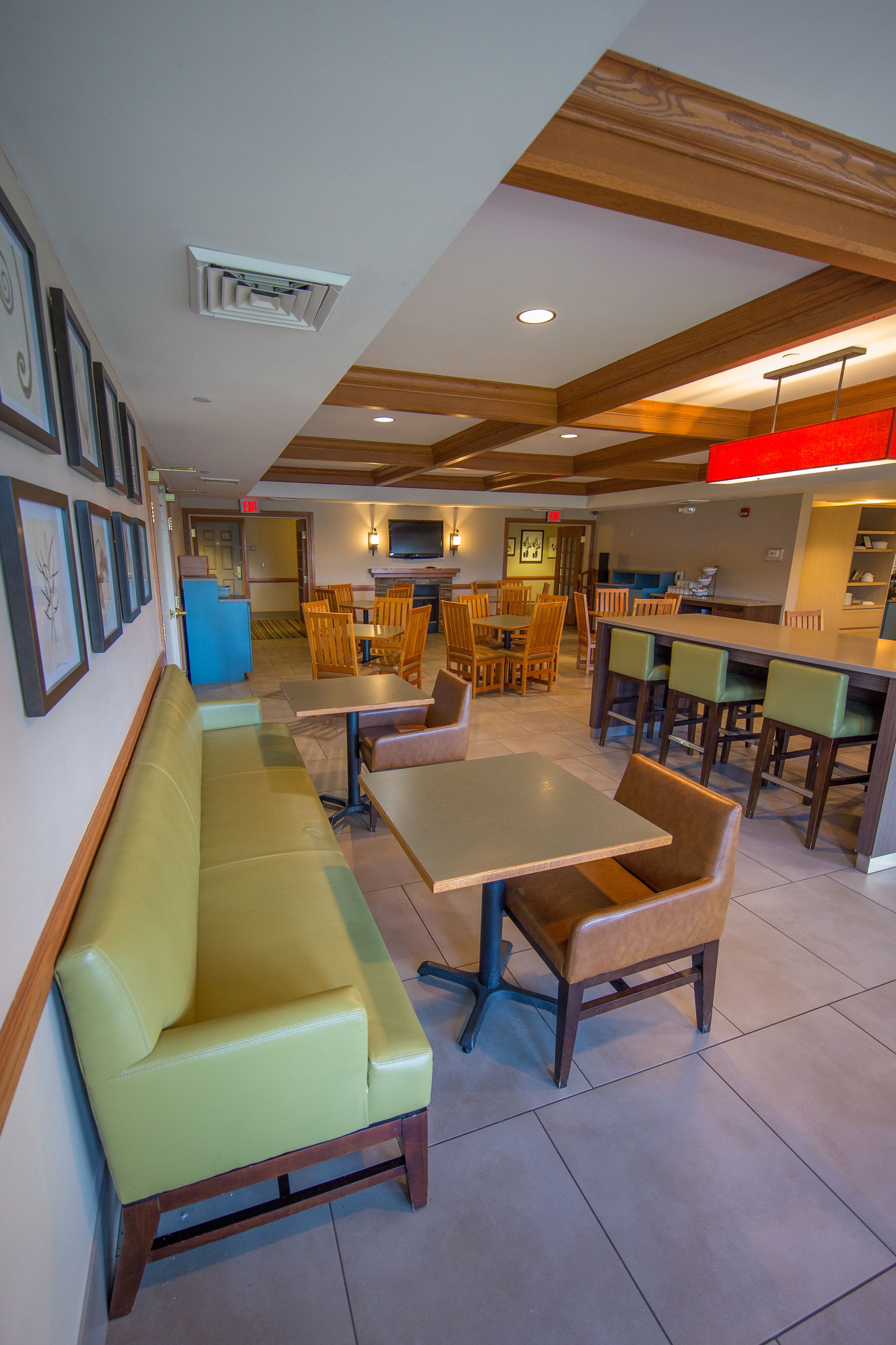 A restaurant with wooden ceiling beams, a long counter with bar stools, and a seating area with tables and chairs.