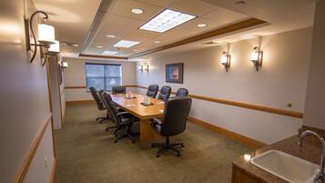A conference room with a long table, chairs, and a sink.