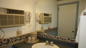 Un baño con lavamanos, dos secadores de pelo y un espejo.