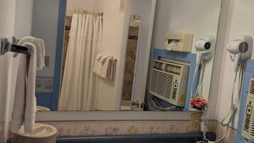 A bathroom with a sink, mirror, towel rack, and hair dryers.
