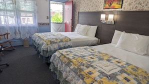 Habitación de hotel con dos camas, una mecedora, una puerta y una ventana con cortinas.