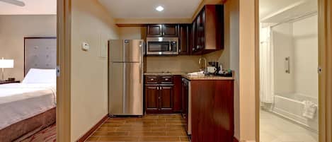 Una habitación de hotel compacta con kitchenette, cama y baño.