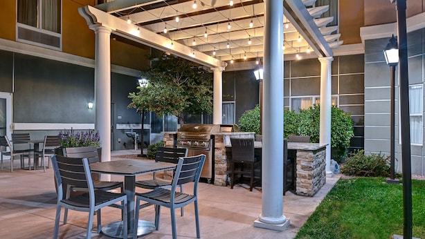 An outdoor patio with a pergola, grilling area, and seating.