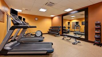 A gym with treadmills, dumbbells, and a mirror.