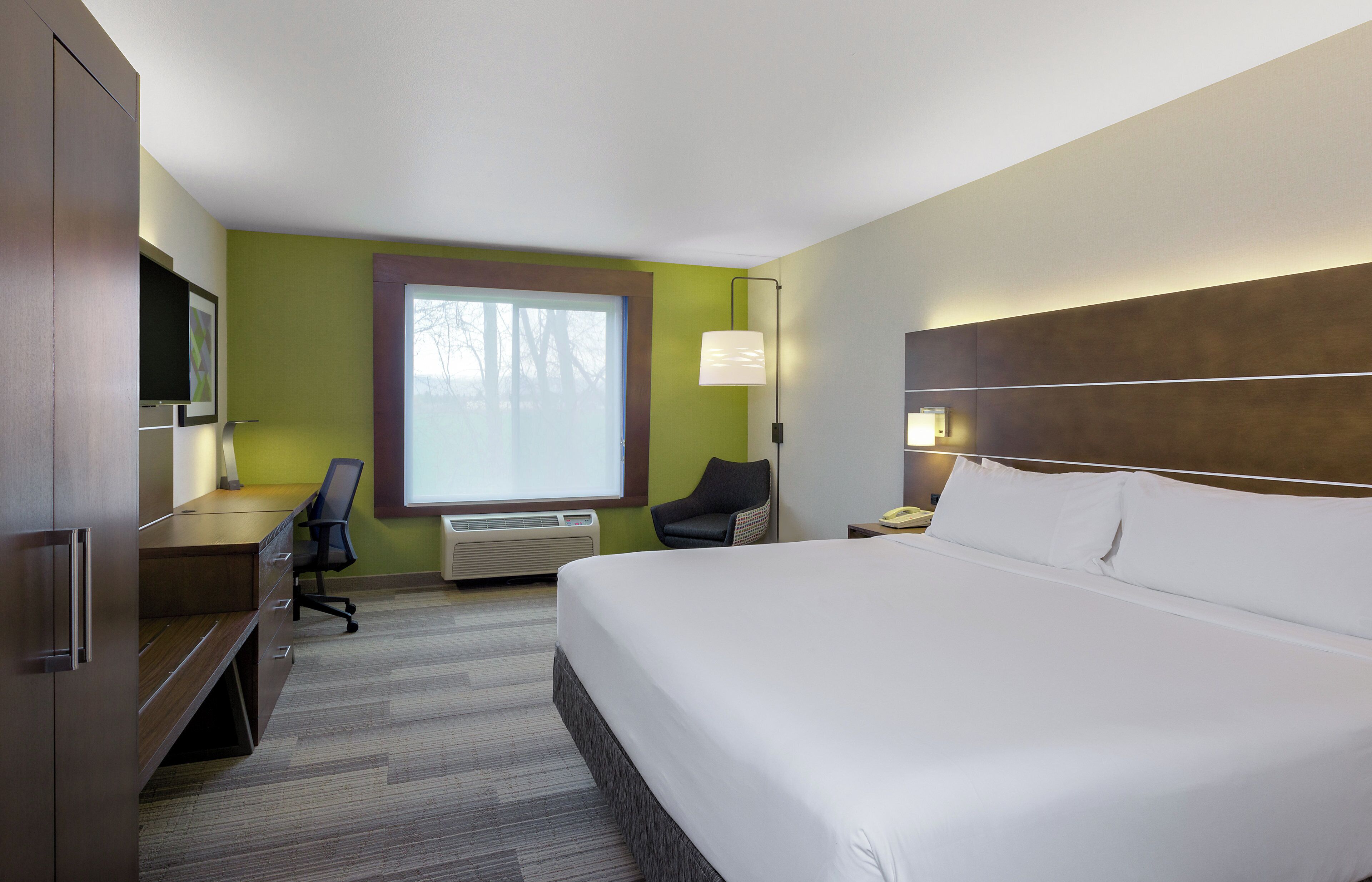 Habitación de hotel con una cama grande, un escritorio, una silla, un televisor y una ventana.