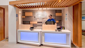 A reception desk with a modern design, featuring a wooden ceiling and a sign that reads "Holiday Inn Express".