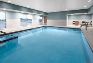 A large indoor swimming pool with clear blue water, surrounded by a tiled deck and a seating area with chairs. - Holiday Inn Express Ellensburg by IHG (Ellensburg)