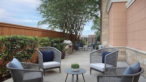 Une terrasse extérieure aménagée avec des meubles en osier, une petite table et un barbecue.