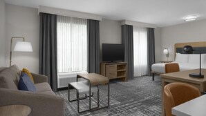 Une chambre d’hôtel équipée d’un lit, d’un bureau, d’une télévision, d’un canapé et d’une chaise.