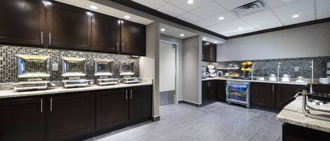 A modern kitchen with dark cabinets, a tiled backsplash, and a countertop with various appliances.