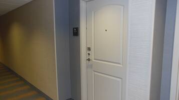 A hallway with a white door, a wall-mounted sign with the number 223, and a carpeted floor.