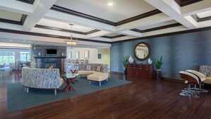 A spacious living room with a fireplace, a large round mirror, and a dining area with a table and chairs. - Homewood Suites by Hilton Louisville-East (Louisville)