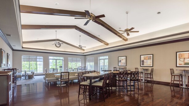 A spacious dining area with high ceilings and multiple ceiling fans, large windows providing natural light, and a variety of seating arrangements including tables and chairs. - Homewood Suites by Hilton Louisville-East (Louisville)