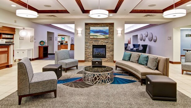A spacious lobby with a fireplace, comfortable seating, and a kitchen area. - Homewood Suites by Hilton Bentonville-Rogers (Rogers)