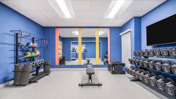 A gym with exercise equipment, a treadmill, and a mirror.