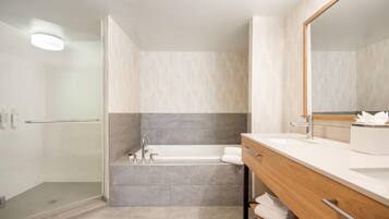 A modern bathroom with a bathtub, a vanity with a mirror, and a shower area.