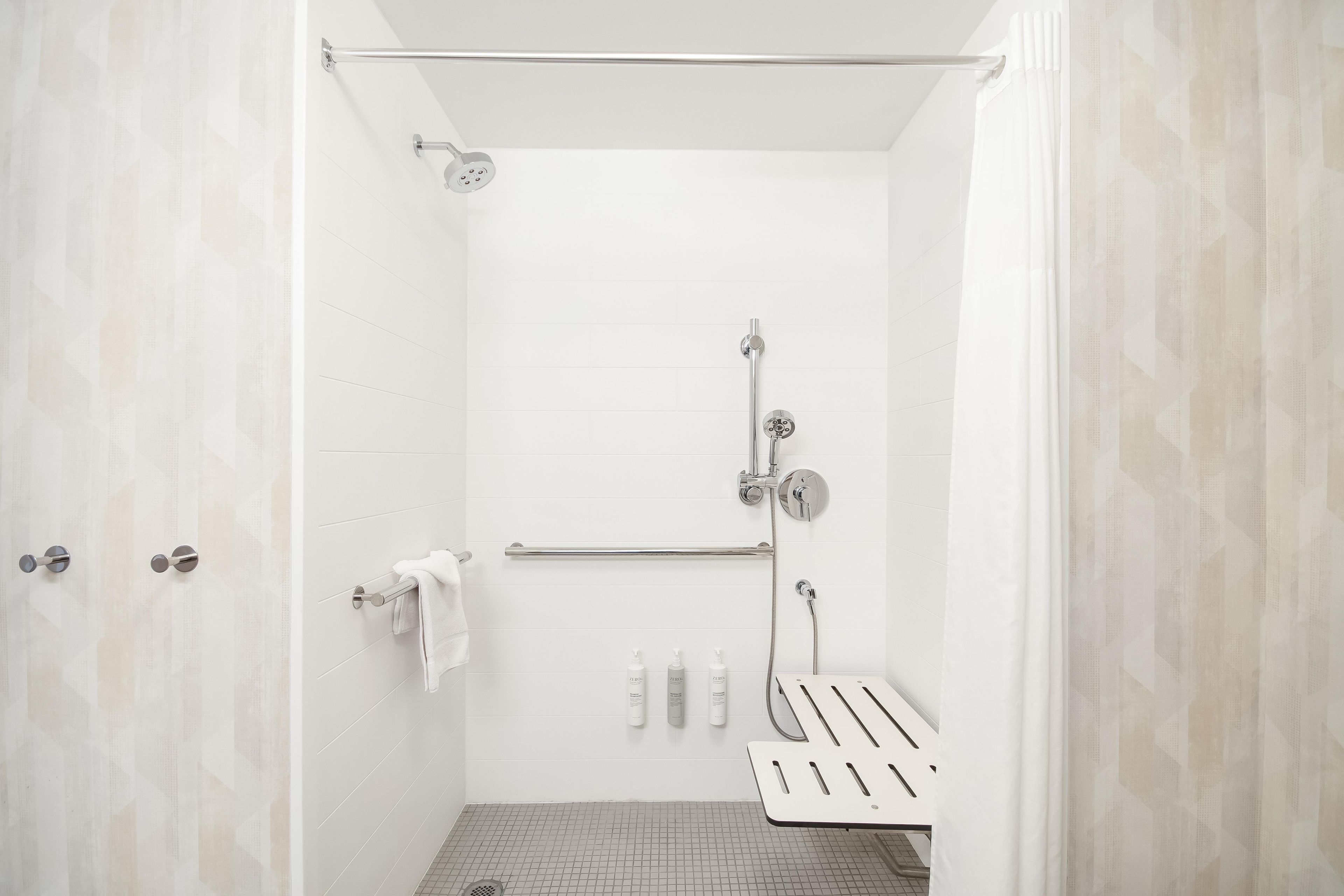A modern shower with a handheld showerhead, a towel rack, and a shower control panel.