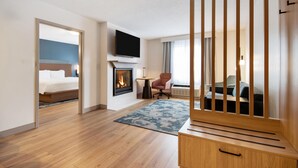 A hotel room with a bed, a TV, a fireplace, a desk, and a chair.