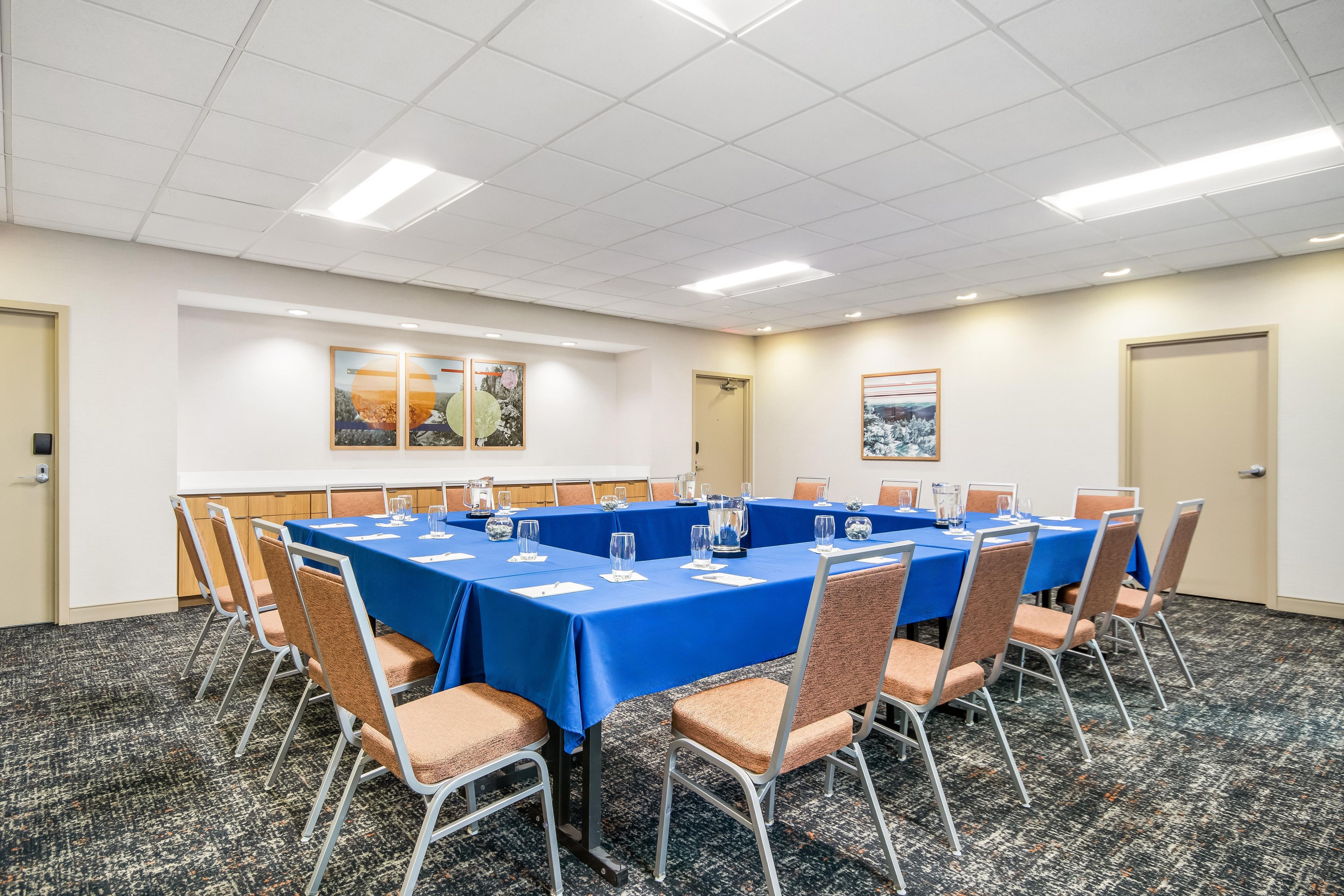 A conference room with a blue tablecloth, chairs, and a carpeted floor.