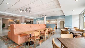 A modern hotel lobby with a seating area, tables, and a reception desk.