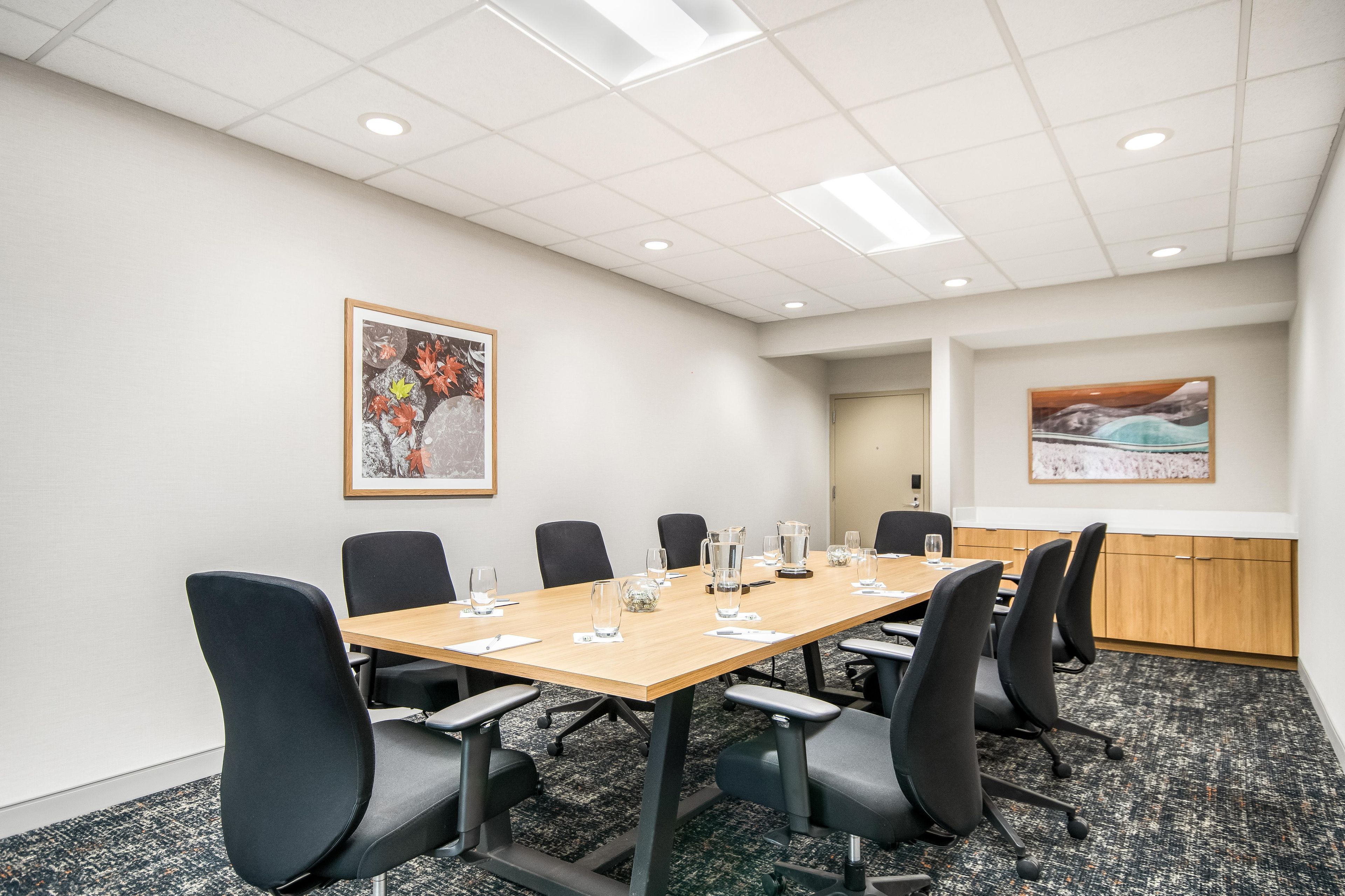 A conference room with a long table, chairs, and artwork on the walls.