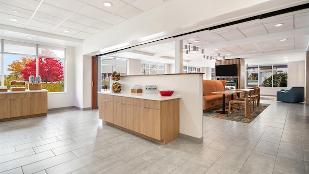 A modern interior with a wooden counter, seating area, and large windows.