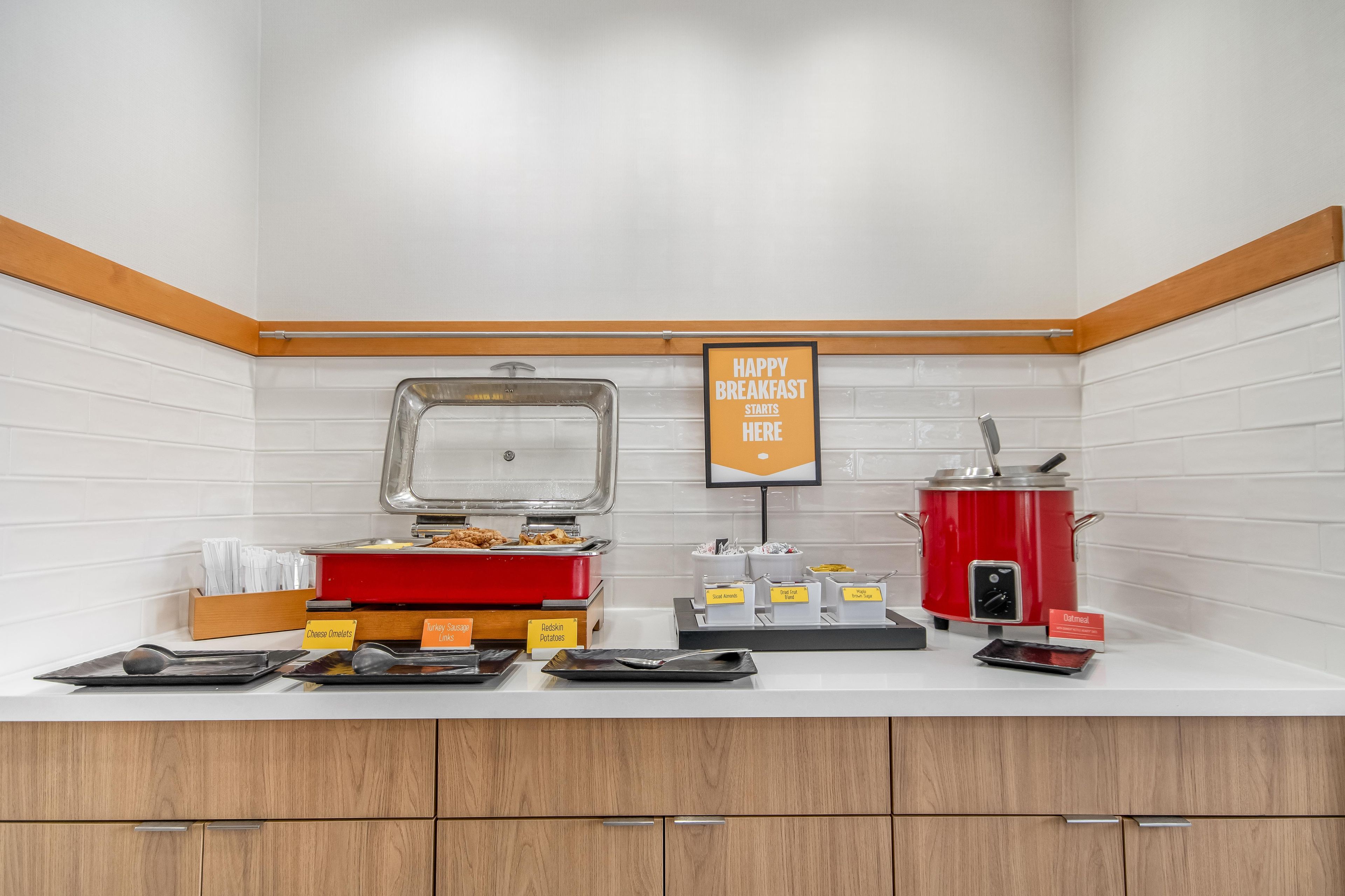 Un buffet de petit-déjeuner avec différents stands proposant des plats variés, notamment des omelettes, des saucisses de dinde et des pommes de terre rouges.