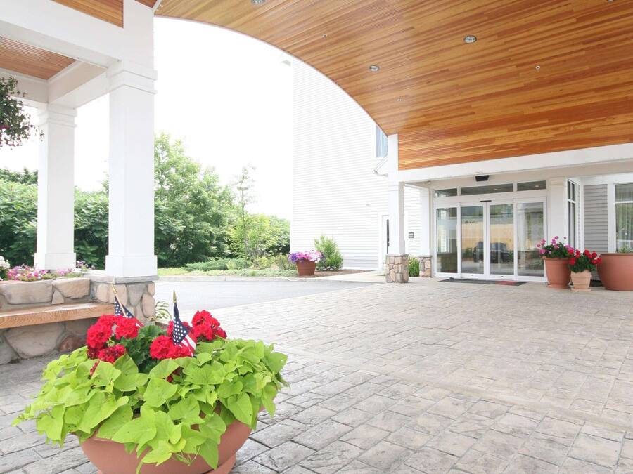 A covered outdoor area with a wooden ceiling, potted plants, and a bench.