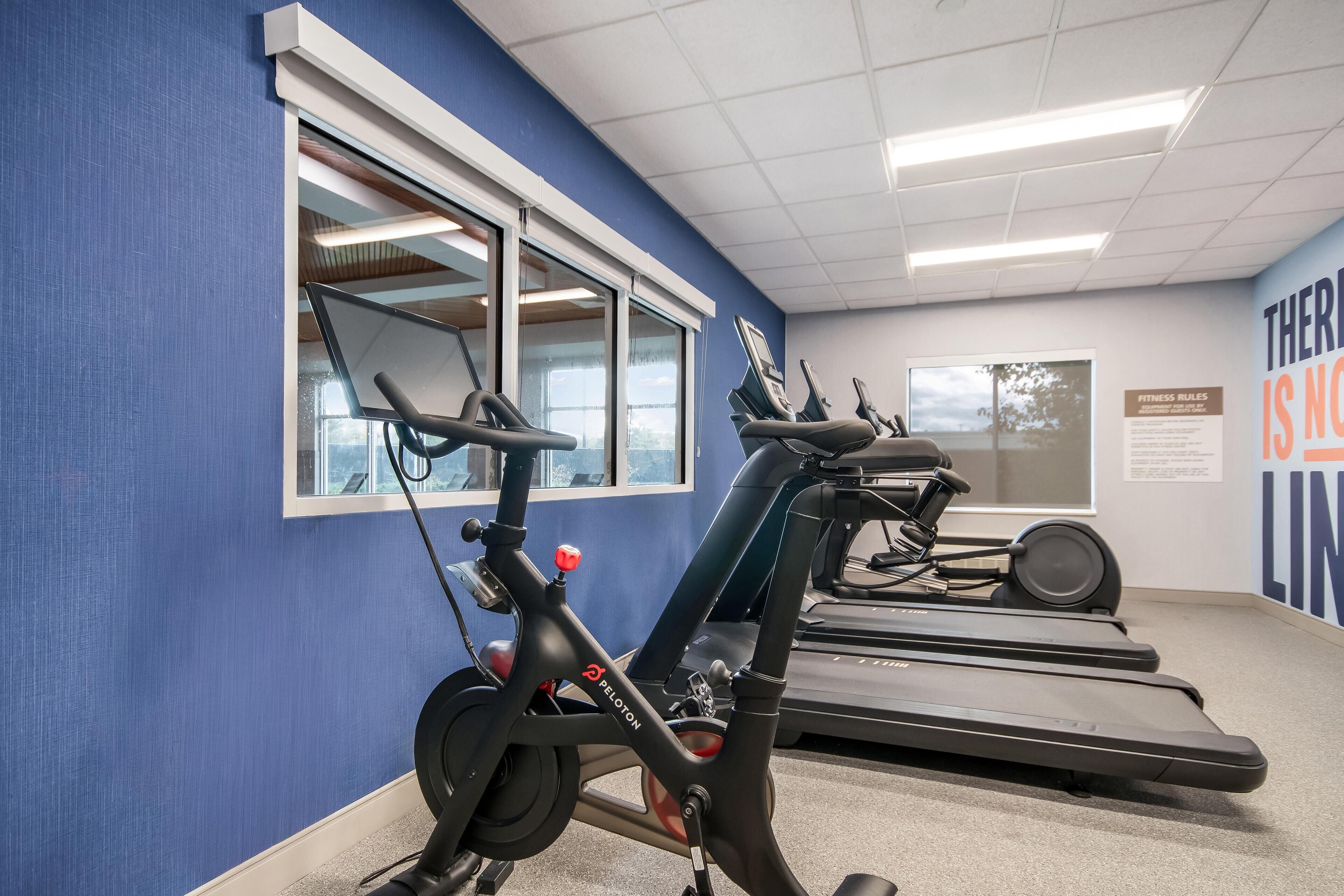 A gym with exercise equipment including a Peloton bike and treadmills.