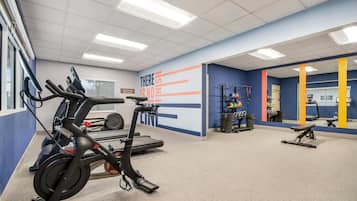 A gym with exercise equipment, a motivational wall, and a mirror.