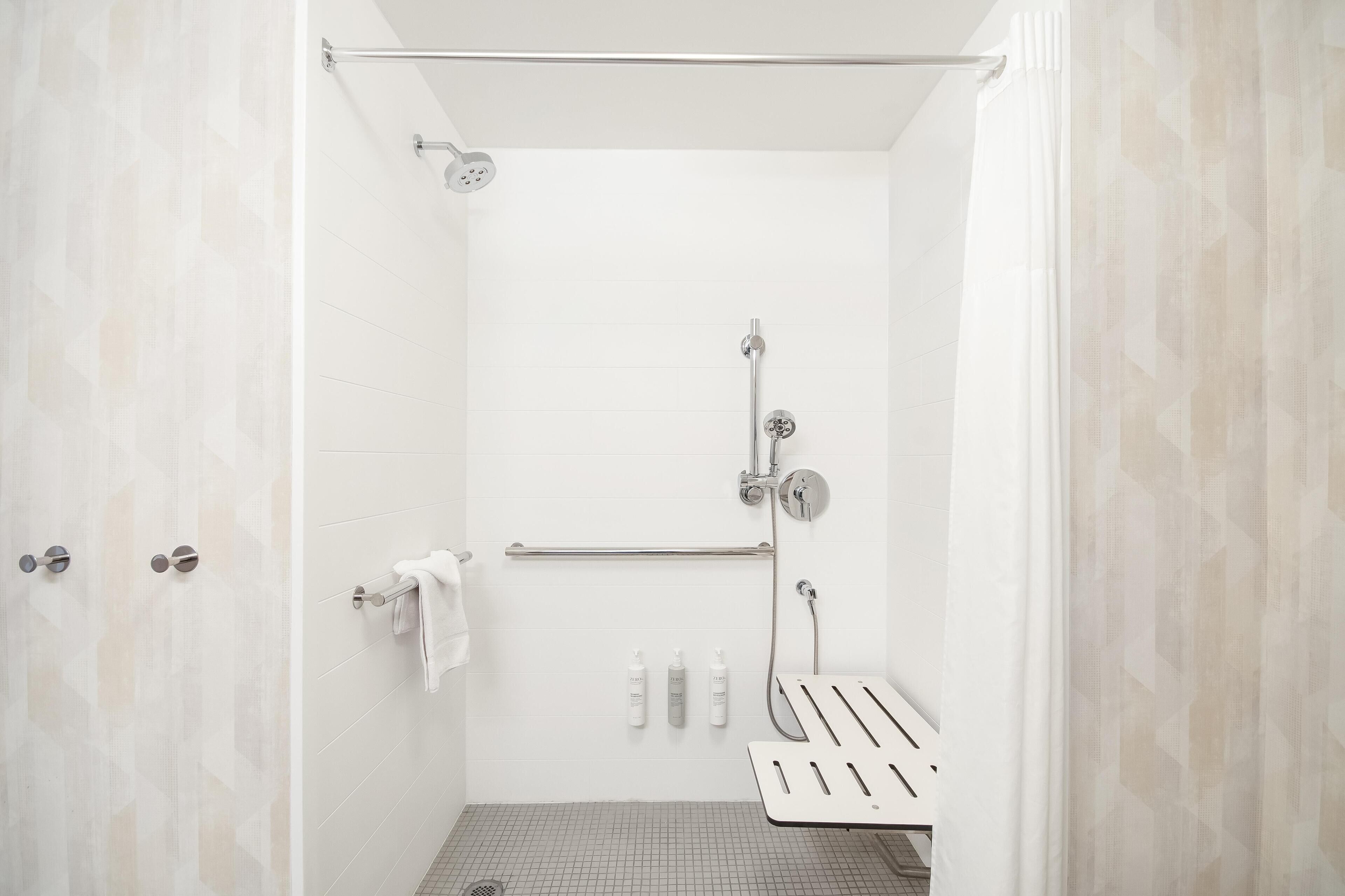 A modern shower with a handheld showerhead, a handheld shower attachment, and a wall-mounted faucet.