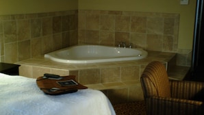 A bathroom with a bathtub, a chair, and a bed. - Hampton Inn Vidalia (Vidalia)