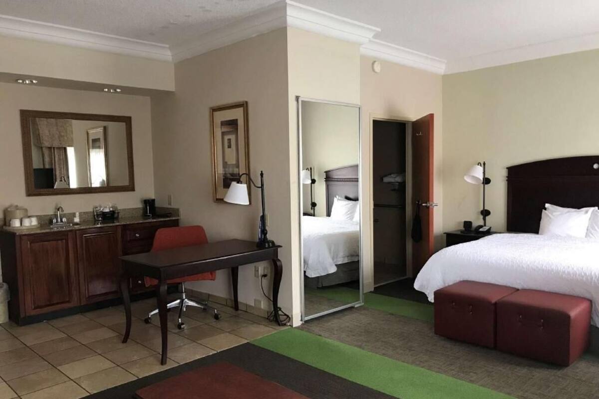 A hotel room with a bed, a desk, a chair, a wardrobe, and a bathroom.