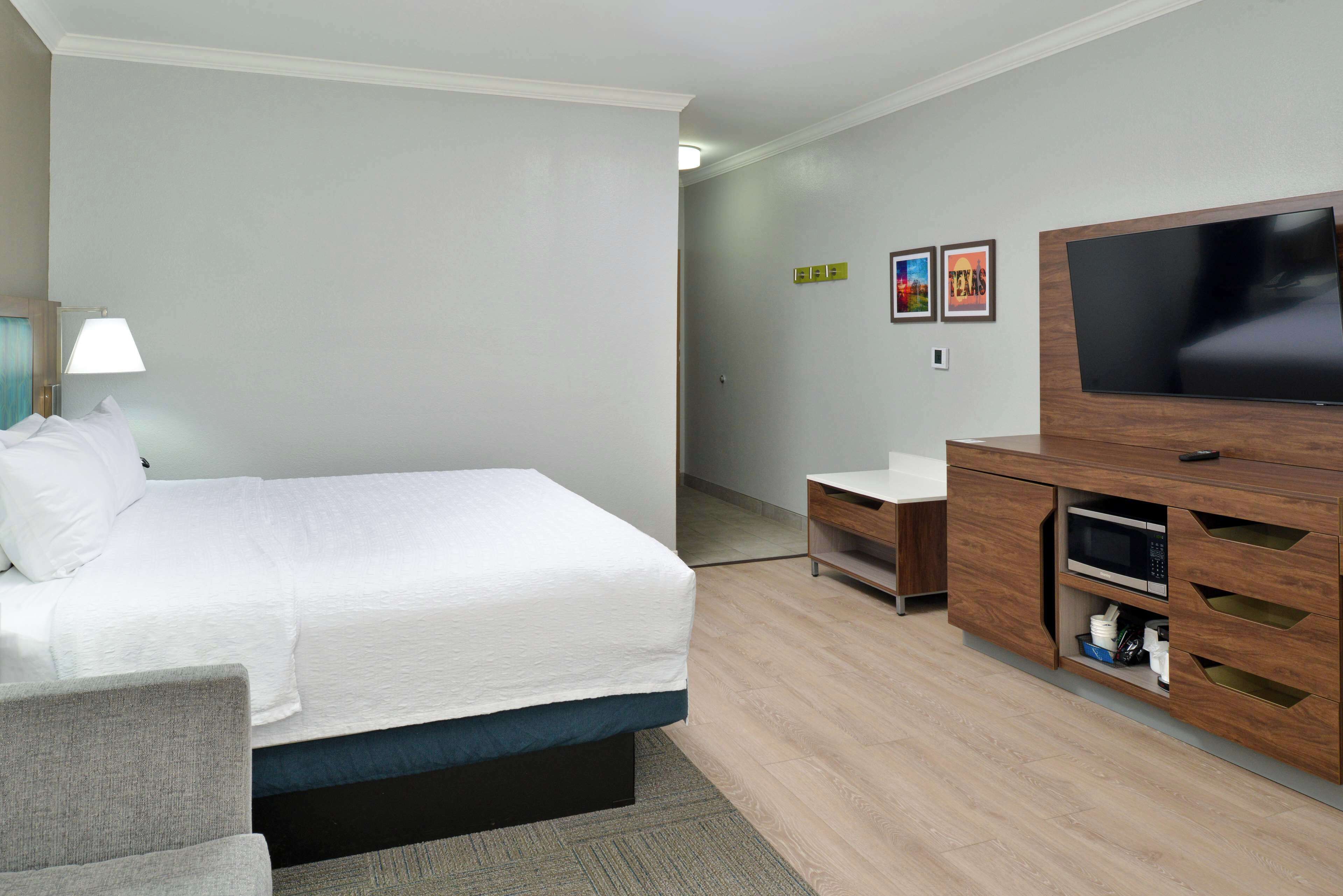 A hotel room with a bed, a desk, a television, and a microwave.