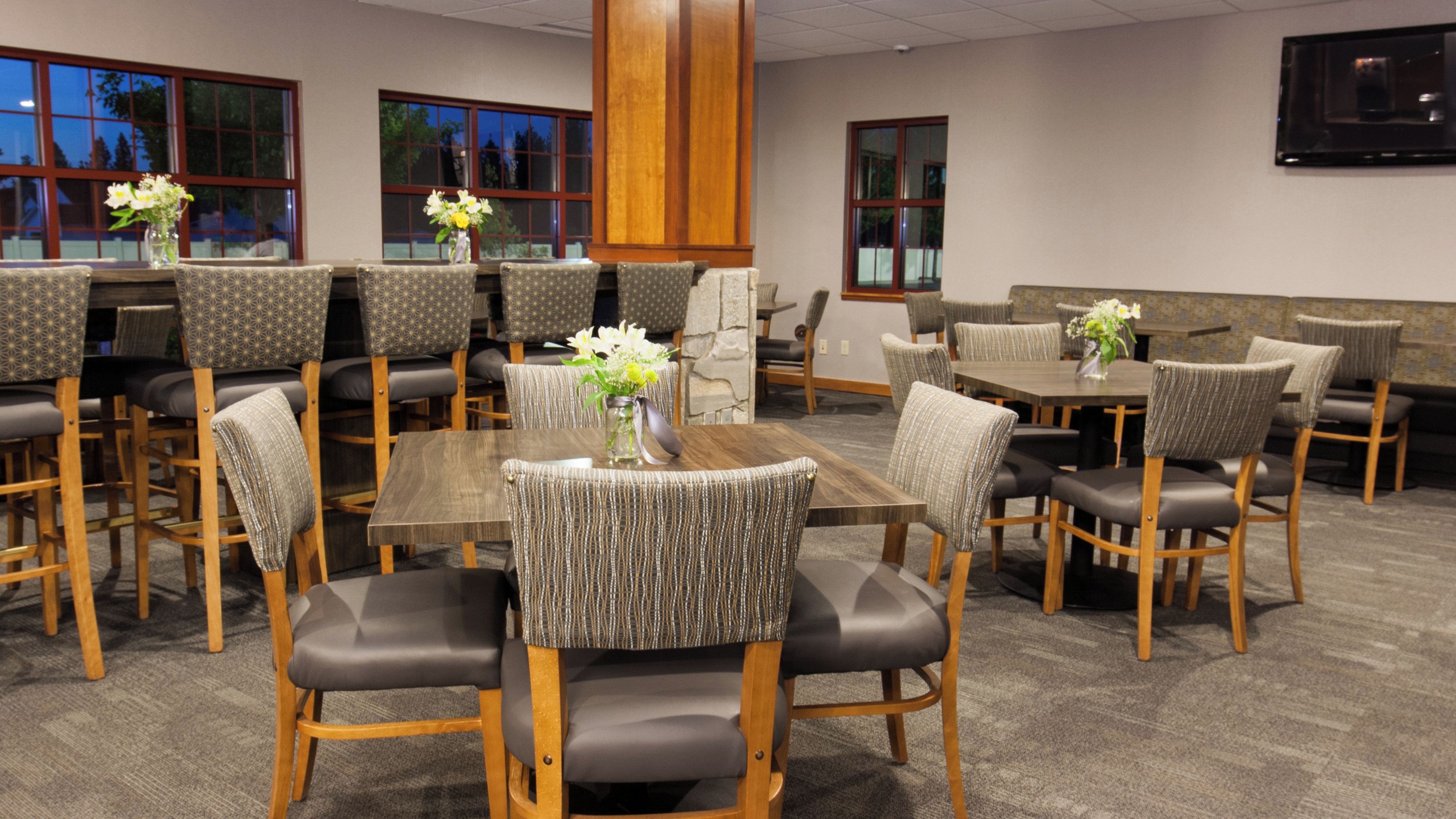 A conference room with multiple tables and chairs, some with floral centerpieces.