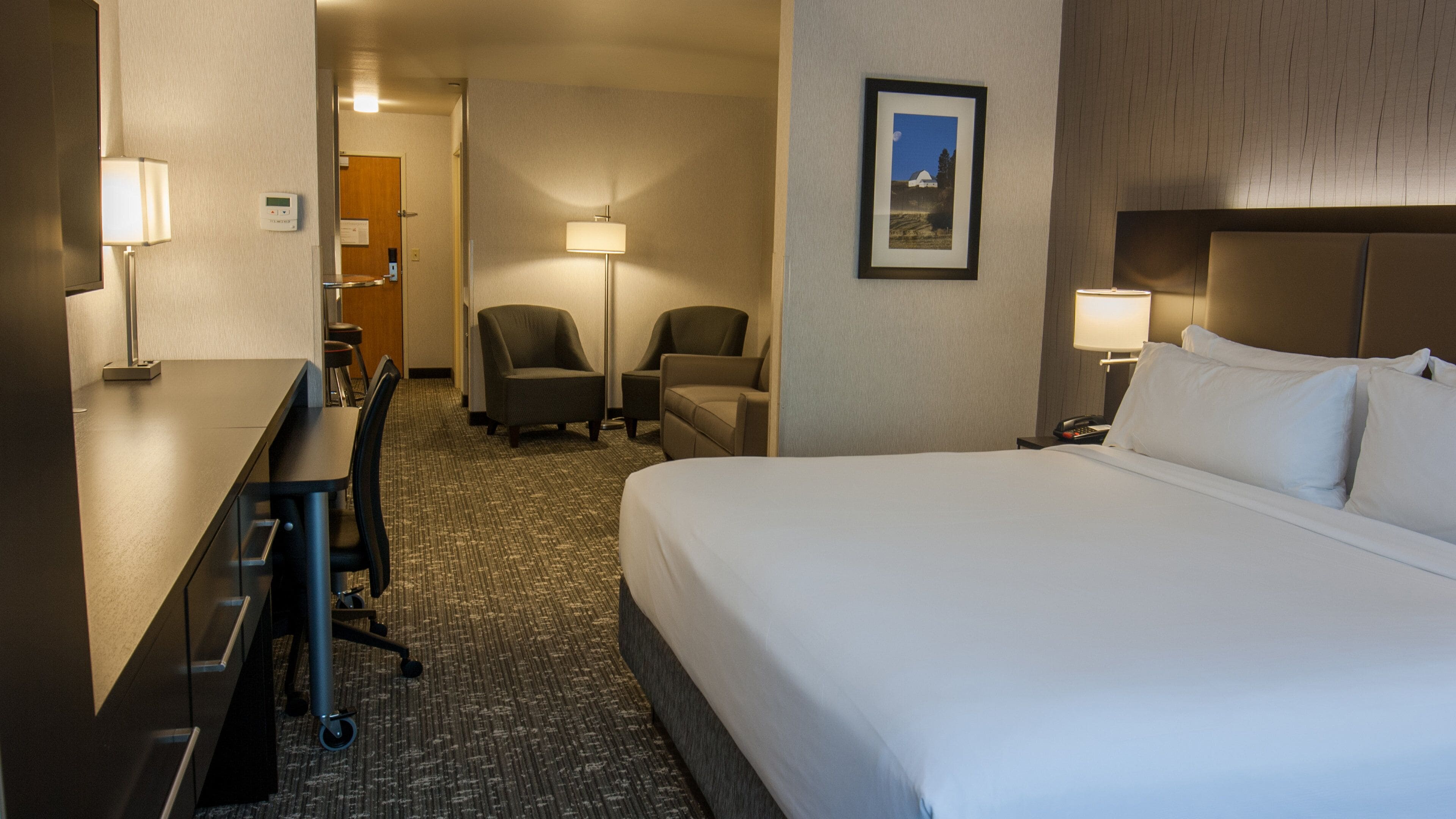 Une chambre d’hôtel équipée d’un lit, d’un bureau, de chaises et de lampes.