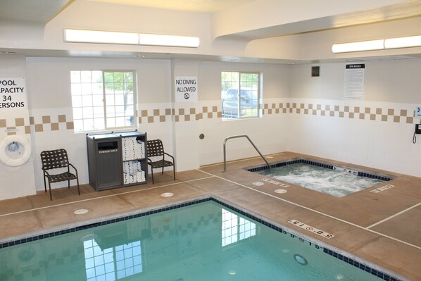 Un espace piscine comprenant deux bassins distincts, un point de distribution de serviettes et une chaise. Des panneaux indiquent la capacité maximale de chaque bassin et interdisent les plongeons.