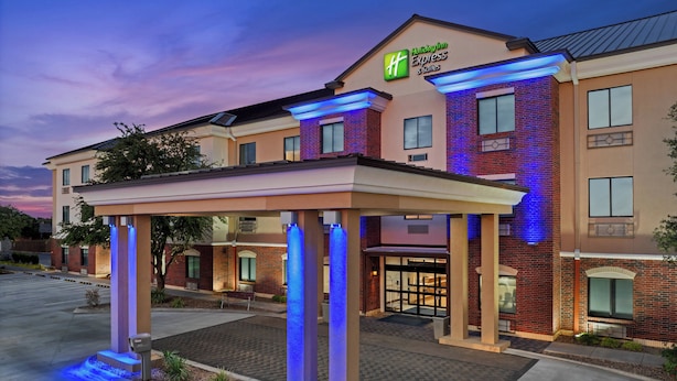 A Holiday Inn Express & Suites building with a covered entrance and illuminated pillars.