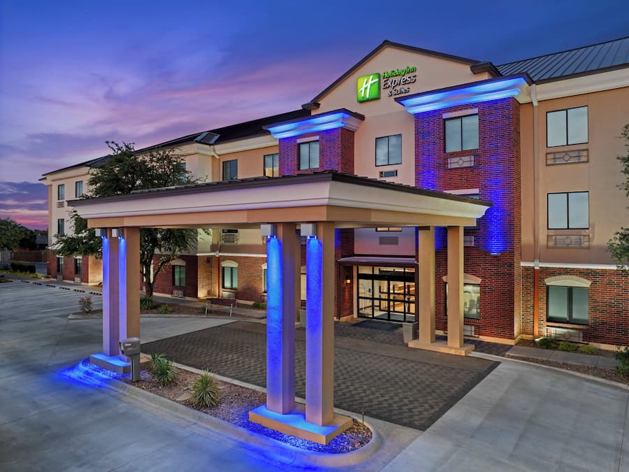 A Holiday Inn Express & Suites building with a covered entrance and illuminated pillars.