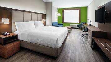 A hotel room with a large bed, a desk, a chair, a TV, and a window.
