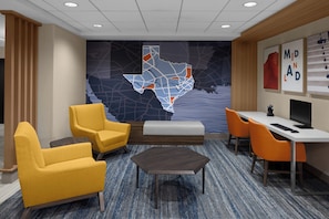 A modern hotel lobby with a map mural, yellow chairs, a desk, and a computer.