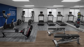 Uma academia com esteiras, elípticos e bancos de musculação.