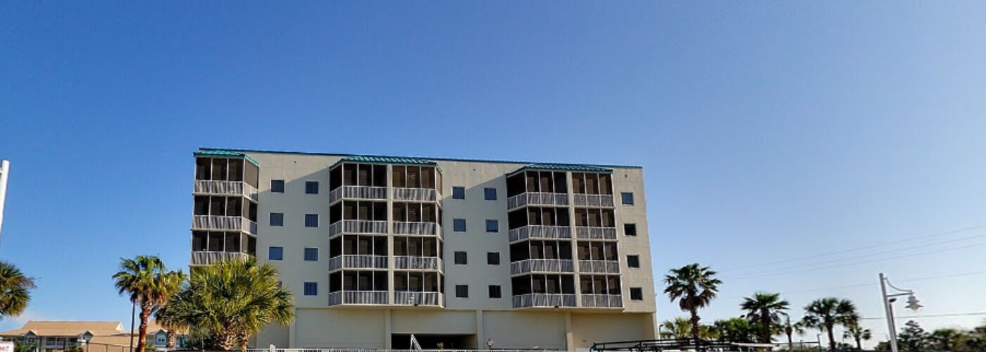Un hotel de varios pisos con balcones, techo plano y cielo azul despejado.