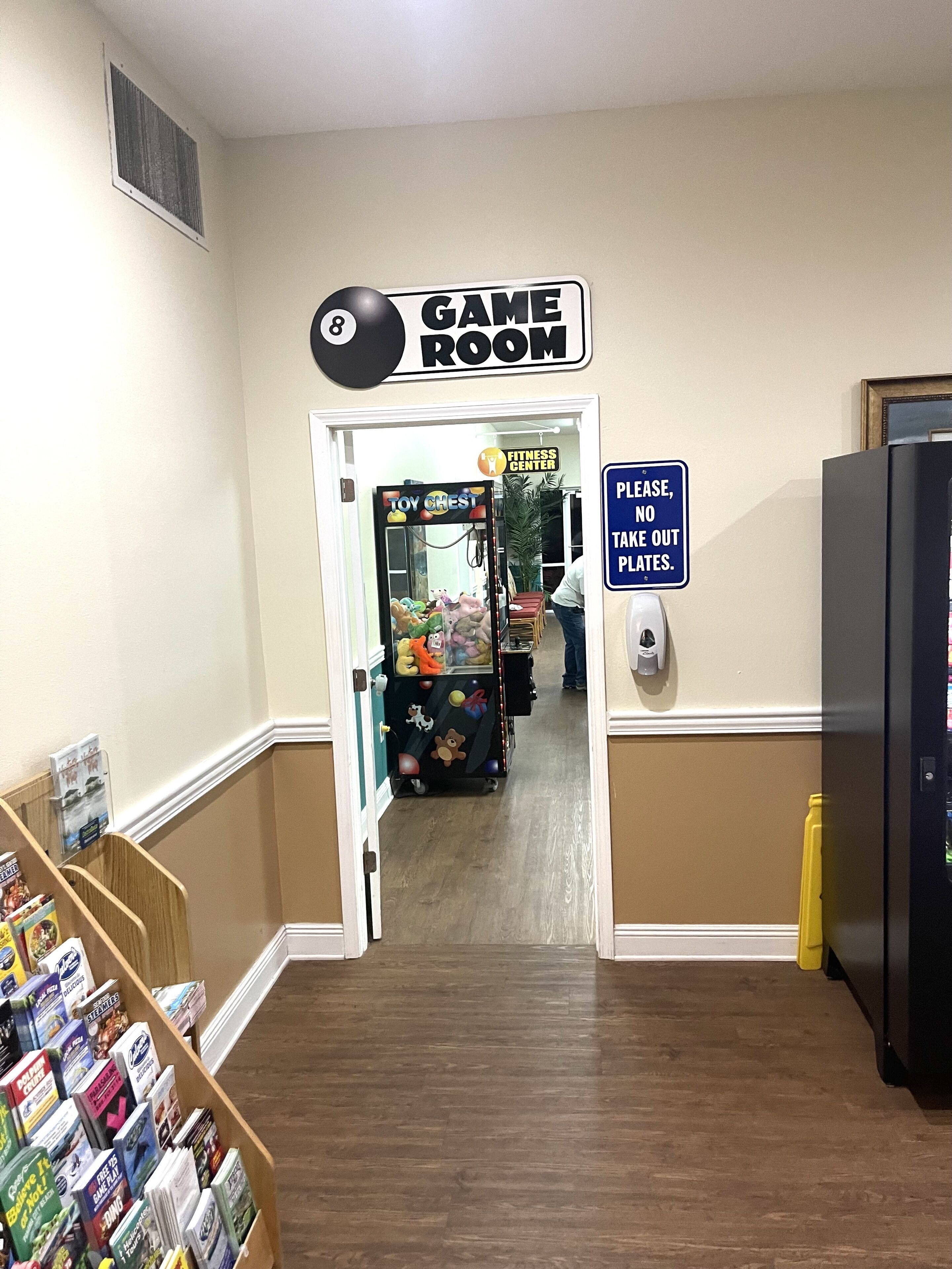 A hallway leading to a game room with a sign indicating its location.