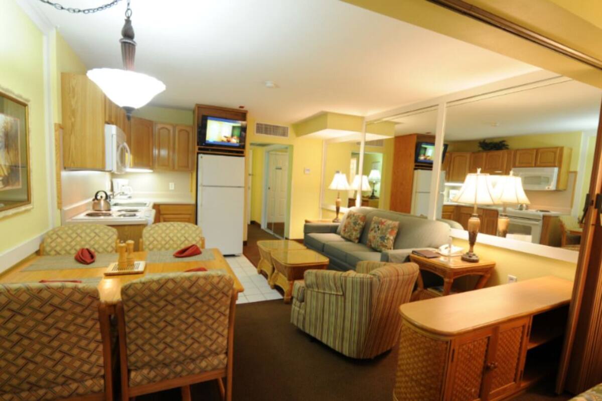 A compact living space with a dining area, sofa, and kitchen.
